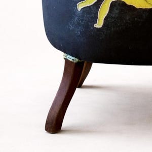 Pu&ograve; includere: Una sedia imbottita blu scuro con un design floreale. La sedia ha gambe in legno scuro. Le gambe sono angolate e hanno una leggera curva. La sedia &egrave; ambientata su uno sfondo bianco.