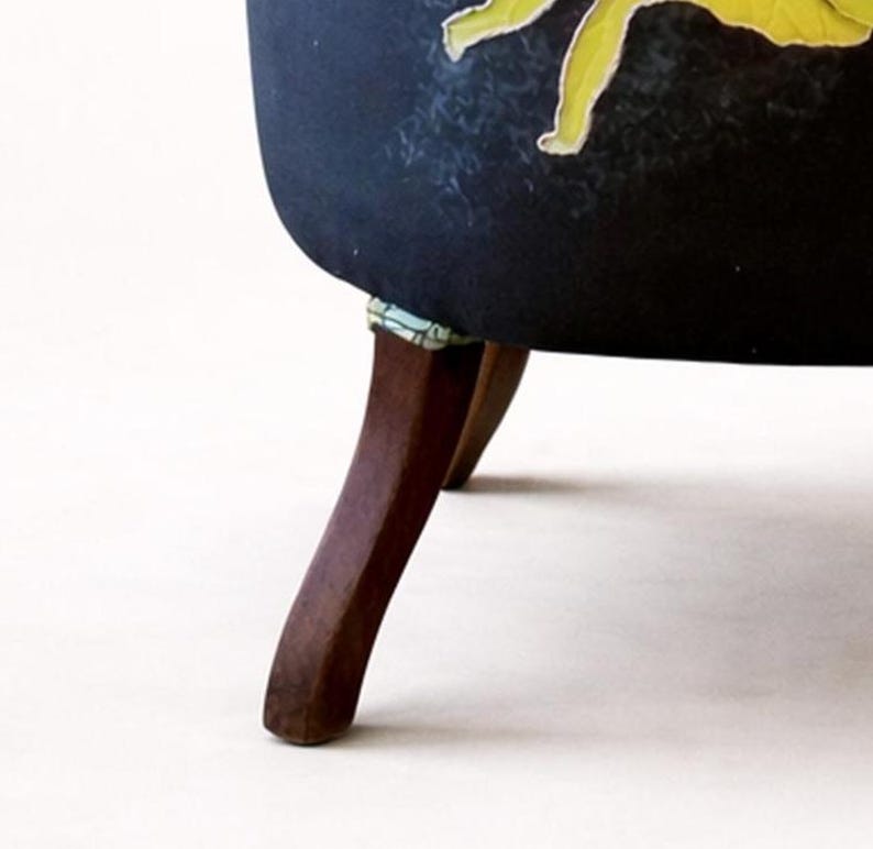 Pu&ograve; includere: Una sedia imbottita blu scuro con un design floreale. La sedia ha gambe in legno scuro. Le gambe sono angolate e hanno una leggera curva. La sedia &egrave; ambientata su uno sfondo bianco.