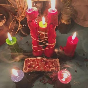 Pu&ograve; includere: Una collezione di candele accese in vari colori, tra cui rosso, verde, giallo e viola. Due candele rosse sono legate con dello spago. Un piccolo pezzo di carta con macchie rosse &egrave; al centro. La scena &egrave; ambientata su una superficie turchese.