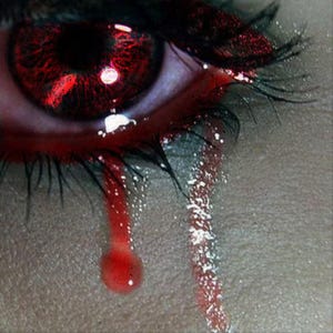 May include: A close-up of an eye with a vibrant red iris and dark, detailed pupil. Long, dark eyelashes frame the eye, and two distinct, vertical red streaks resembling tears run down the skin below the lower eyelid, creating a high-contrast visual.