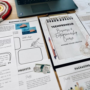 May include: A notebook with the title "Teenpreneur: Business & Entrepreneurship Course" by Wonder House Creative. The notebook is open to a page with the heading "Packaging" and text about how to package a product. The notebook is on a table with other papers, including a business card design template and a reflection page with the quote "Business ideas are like spaghetti, throw them against the wall and see what sticks."