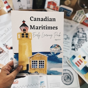 Pode incluir: Um farol amarelo e branco com um telhado vermelho e um fundo de céu azul. O texto na frente do livreto diz "Canadian Maritimes Early Learning Pack Ages 3-7 Waypoints".