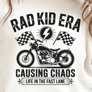 Può includere: Maglietta bianca con una grafica nera di una motocicletta con il testo "Rad Kid Era Causing Chaos Life in the Fast Lane"