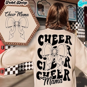 May include: A cream-colored sweatshirt with a black graphic design that says "CHEER" with a large bow in the middle and "Mama" at the bottom. The graphic is in a retro style font.