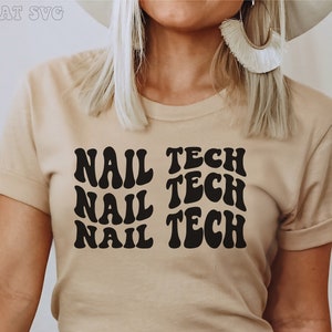 Op de afbeelding: Een beige T-shirt met de tekst "NAIL TECH" die drie keer wordt herhaald in een retro lettertype.