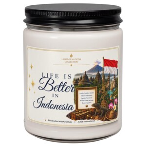 May include: A white candle in a glass jar with a black lid. The label features the text "Life is Better in Indonesia" and "Light of Nations Collection," alongside an illustration of a volcano, the Indonesian flag, and a Komodo dragon.