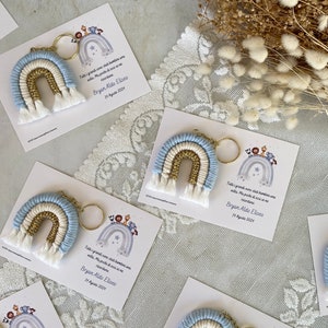 Könnte beinhalten: Ein Set aus vier blauen, weißen und goldenen Regenbogen-Schlüsselanhängern mit einem Anhänger an jedem. Der Anhänger enthält eine Nachricht in italienischer Sprache, die lautet: "Tutti i grandi sono stati bambini una volta. Ma pochi di essi se ne ricordano." Der Anhänger enthält auch den Namen "Bryan Aldo Eliseo" und das Datum "14 Agosto 2024".