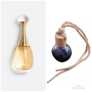 May include: A gold and clear glass bottle of perfume with a gold cap and a clear glass dropper. The bottle is shaped like a teardrop. Next to it is a small, round, blue glass bottle with a wooden cap and a brown rope attached to it.