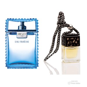 May include: A blue glass bottle of cologne with a black cap and the words "Eau Fraiche" on the front. A small black and gold car air freshener with a black string.
