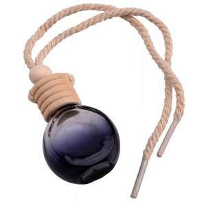 Op de afbeelding: Een donkerblauwe glazen aromatherapie-diffuser met een houten dop en een beige touw om op te hangen. De diffuser heeft een ronde vorm en is ontworpen voor etherische oli&euml;n. Het touw is gemaakt van een gedraaide natuurlijke vezel.