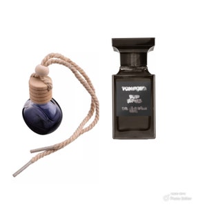 May include: A brown glass bottle with a wooden cap and a blue liquid inside. The bottle is attached to a brown rope with a loop at the top. The bottle is next to a brown glass bottle with a black label that says "Tom Ford Private Blend Noir de Noir Eau de Parfum Spray".