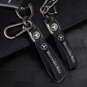 May include: Two black leather keyrings with silver metal key rings and a silver Mercedes-Benz logo. The keychains have the words "Mercedes-Benz" embossed on them.