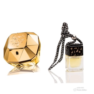 May include: A gold-coloured perfume bottle with a diamond-shaped design. The bottle is hanging from a black string with a black and gold cap.