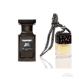 May include: Two bottles of perfume, one larger and one smaller. The larger bottle is black with a silver label that reads "Tom Ford Noir Extreme Eau de Parfum Spray". The smaller bottle is a car air freshener with a black and gold design.