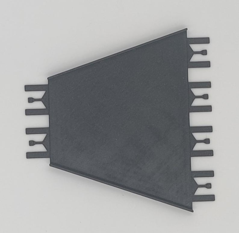 May include: A black plastic corner tile trim piece with a triangular shape and a series of small teeth along the edges.