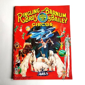 May include: A vintage program for the Ringling Bros. and Barnum & Bailey Circus. The cover features a red background with the circus name in white and gold lettering. The program is filled with colorful illustrations of circus performers, animals, and acts. The text on the cover reads "The Greatest Show on Earth".