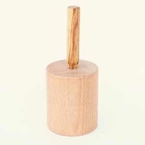 以下が含まれることがあります： 上部に木製のノブが付いた木製の円筒。円筒は薄い茶色で、ノブは濃い茶色です。