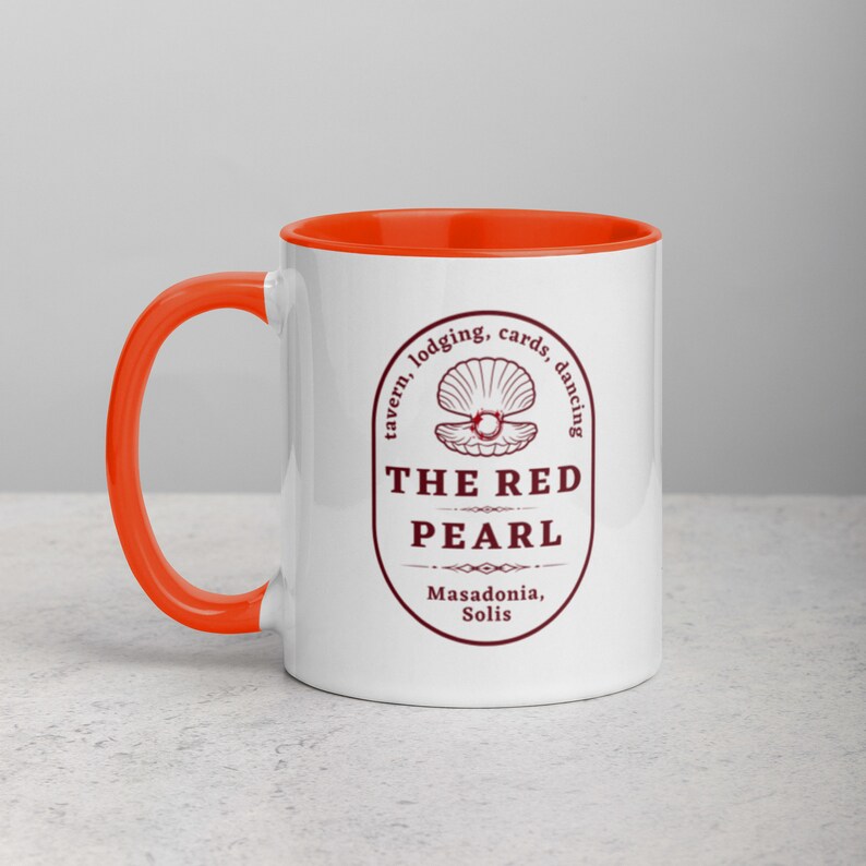Close-up studio shot of a white ceramic mug with an orange handle and interior. The mug is oriented with the handle facing towards the left. Centered on the mug is a maroon-colored oval logo containing "The Red Pearl" in bold sans-serif letters. Above this title is shell graphic, around logo text include tavern, lodging, cards, dancing, and location "Masadonia, Solis". The image has balanced lighting and is placed against a gradient soft gray background.