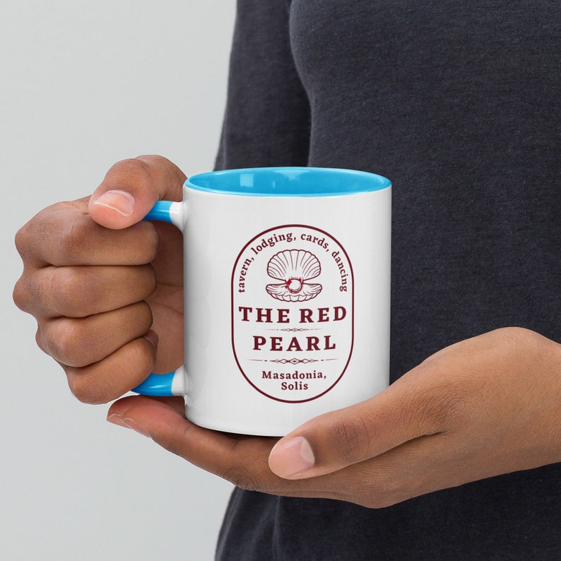 May include: White ceramic mug with a blue rim. The mug features a red logo with the text "The Red Pearl" and a stylized image of a pearl inside a seashell. The logo also includes the text "tavern, lodging, cards, dancing" and "Masadonia, Solis".