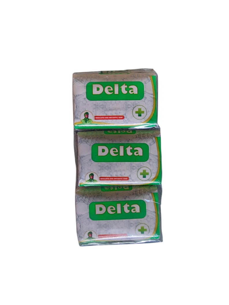 Puede incluir: Tres barras apiladas de jab&oacute;n Delta medicado y antis&eacute;ptico. Cada barra est&aacute; envuelta en papel blanco con texto verde y un signo m&aacute;s verde. El logotipo de Delta es verde.