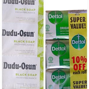 Puede incluir: La imagen muestra tres barras de jab&oacute;n negro Dudu-Osun y tres barras de jab&oacute;n antibacteriano Dettol. El jab&oacute;n Dudu-Osun tiene un embalaje blanco con detalles verdes. El jab&oacute;n Dettol est&aacute; en un embalaje verde y blanco con una pancarta promocional amarilla.