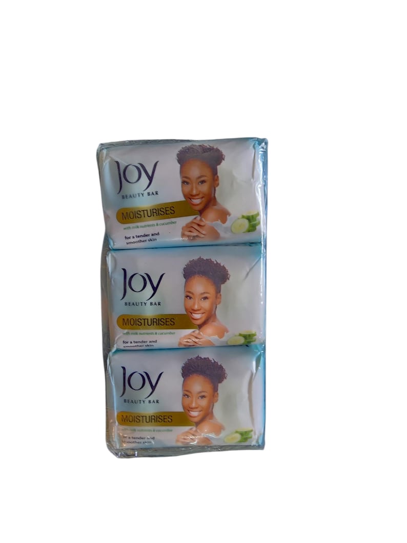 Puede incluir: Tres barras de jab&oacute;n Joy Beauty Bar envueltas. Cada barra presenta la imagen de una mujer y las palabras "Joy BEAUTY BAR MOISTURISES" con texto sobre nutrientes de leche y pepino. El jab&oacute;n est&aacute; dise&ntilde;ado para una piel m&aacute;s suave y tersa.