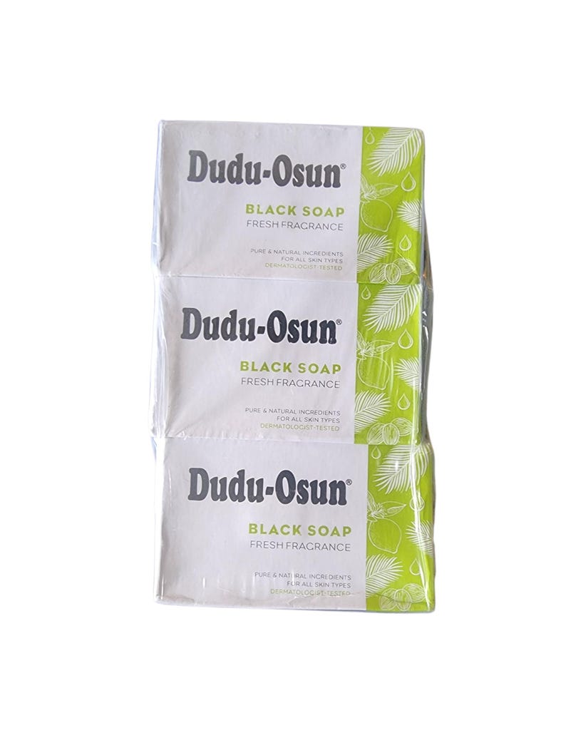 Puede incluir: Tres barras envueltas de jab&oacute;n negro Dudu-Osun. El embalaje blanco presenta el nombre de la marca y los detalles del producto en texto negro, con un dise&ntilde;o de hojas verdes y blancas en el lateral. El jab&oacute;n se anuncia como de fragancia fresca e ingredientes naturales.
