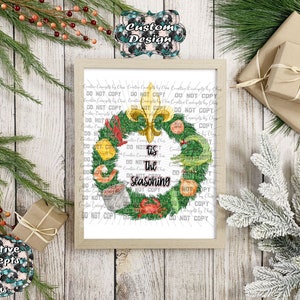 May include: A framed print featuring a green wreath decorated with a gold fleur-de-lis, a crawfish, a shrimp, a crab, and a pot of food. The text in the center reads 'Tis the Seasoning' in black script and block lettering on a white background.