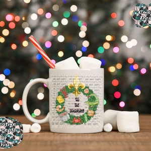 May include: A white ceramic mug filled with marshmallows and a red and white striped straw. The mug features a green wreath graphic with a gold fleur-de-lis, seafood illustrations, and the black text 'tis the seasoning' in the center.