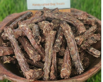 Puede incluir: Un cuenco de madera grande lleno de numerosas golosinas para perros secas, marrones y texturizadas. Detrás del cuenco hay una bolsa de color tostado y blanco con el texto "YOUR DOG'S KITCHEN" y "Handcrafted Dog Treats" en la etiqueta.