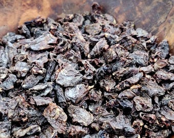 Puede incluir: Un cuenco de madera grande lleno de una generosa porción de trozos de carne deshidratada de color marrón oscuro. Los trozos secos tienen una textura rugosa e irregular y un color profundo y concentrado, pareciendo pequeños bocados.