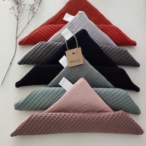 Puede incluir: Un conjunto de siete cuadrados de tejido de tejido de waffle en varios colores, incluyendo rojo, gris, azul marino, verde y rosa. Los cuadrados est&aacute;n doblados en tri&aacute;ngulos y apilados uno encima del otro. Una peque&ntilde;a etiqueta marr&oacute;n con la palabra "Triebel" est&aacute; unida a uno de los cuadrados.