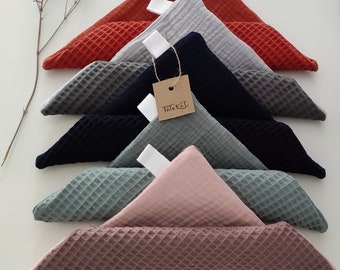 May include: A set of seven waffle weave fabric squares in various colors, including red, gray, navy, green, and pink. The squares are folded into triangles and stacked on top of each other. A small brown tag with the word "Triebel" is attached to one of the squares.