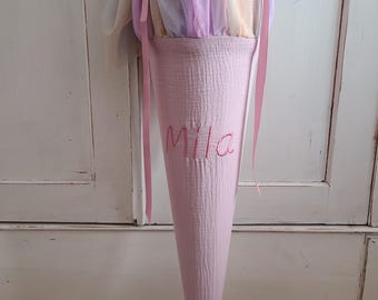 May include: A pink fabric cone with a rainbow tulle top and the name "Mila" embroidered on the front.