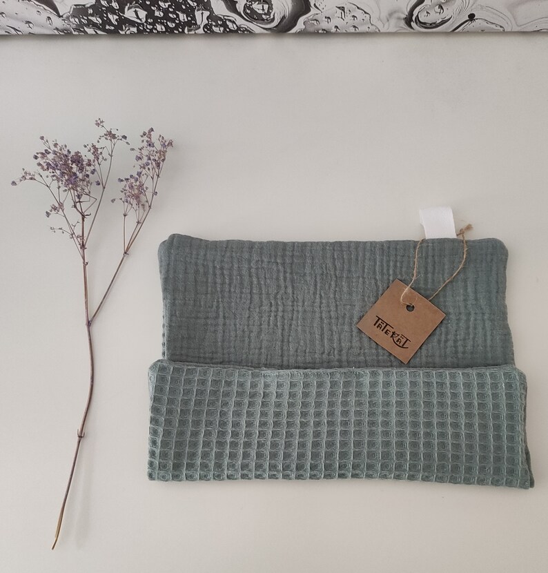 Puede incluir: Un pa&ntilde;o de cocina de tejido de gofre verde salvia con una capa superior de muselina a juego. El pa&ntilde;o de cocina tiene una etiqueta marr&oacute;n con la palabra "Tillex" escrita en ella.