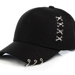 May include: Black baseball cap with silver metal rings on the brim and a row of silver metal eyelets on the back.