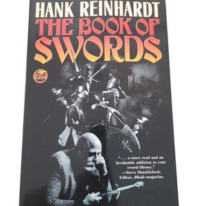 May include: A book cover with a black background and the title "The Book of Swords" in red and yellow lettering. The cover features a black and white illustration of a man in a suit holding a sword, with a medieval battle scene in the background. The text "...a must read and an invaluable addition to your sword library." is quoted from Steve Shackleford, Editor, Blade magazine.