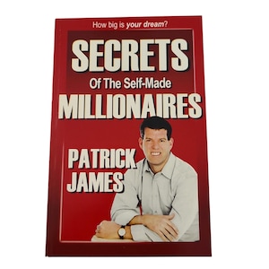 May include: A hardcover book titled "SECRETS Of The Self-Made MILLIONAIRES" by Patrick James. The book has a red cover with white text and a photo of a man in a light-colored shirt. The text "How big is your dream?" is at the top.