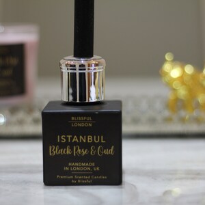 May include: A square black glass reed diffuser bottle with a silver cap and a black reed. The label features gold text reading Blissful London, Istanbul Black Rose & Oud, Handmade in London, UK, and Premium Scented Candles by Blissful.