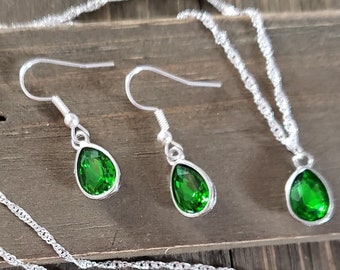May include: A silver necklace and matching earrings with teardrop-shaped green gemstones.