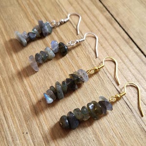 May include: A pair of earrings with silver and gold hooks. Each earring features a stack of dark gray labradorite stones.