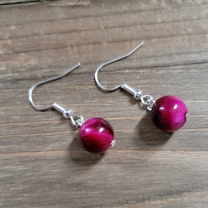 May include: A pair of silver dangle earrings with pink tiger's eye stone beads.