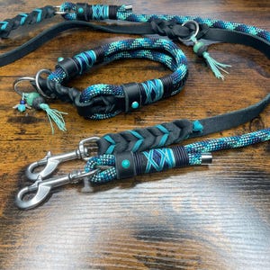 Könnte beinhalten: Ein schwarzes Lederhundekragen- und Leinenset mit türkisfarbenen und blauen geflochtenen Seilakzenten. Die Leine hat zwei Metallclips.
