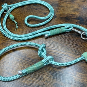 以下が含まれることがあります： シルバーのクリップと革のアクセントが付いた、ティールブルーのロープ製の犬用リード。リードは厚い編み込みロープで作られており、一方の端に首輪に取り付けるためのループが付いています。