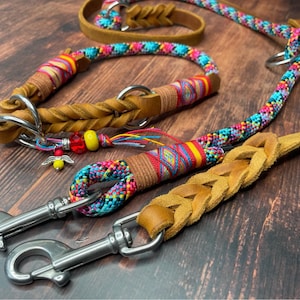 May include: A colorful braided leather dog collar and leash set with a bright red, yellow, blue, and pink pattern. The set includes a matching collar and leash with silver metal clasps.