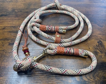 May include: A white, red, and brown patterned rope dog leash with a metal clip and leather accents.