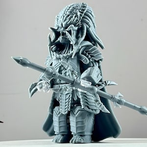 May include: A gray, detailed, 3D printed action figure of a Predator with a spear. The figure is wearing a detailed, armored suit with a cape.