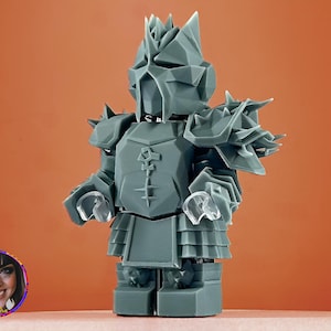 Op de afbeelding: Een grijs 3D-geprint miniatuurfiguur van een ridder die een harnas draagt met spikes en een helm. De figuur staat op een vlak oppervlak.