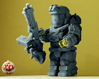 May include: A gray plastic action figure of a soldier wearing a helmet and holding a large gray gun. The figure has yellow accents on the helmet and gun.