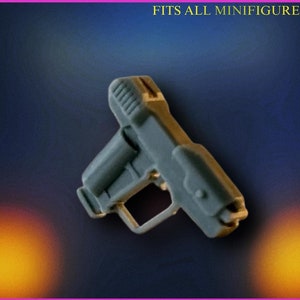 Puede incluir: Una pistola de juguete de plástico gris, diseñada para adaptarse a todas las minifiguras. La pistola tiene un gatillo negro y una superficie texturizada.